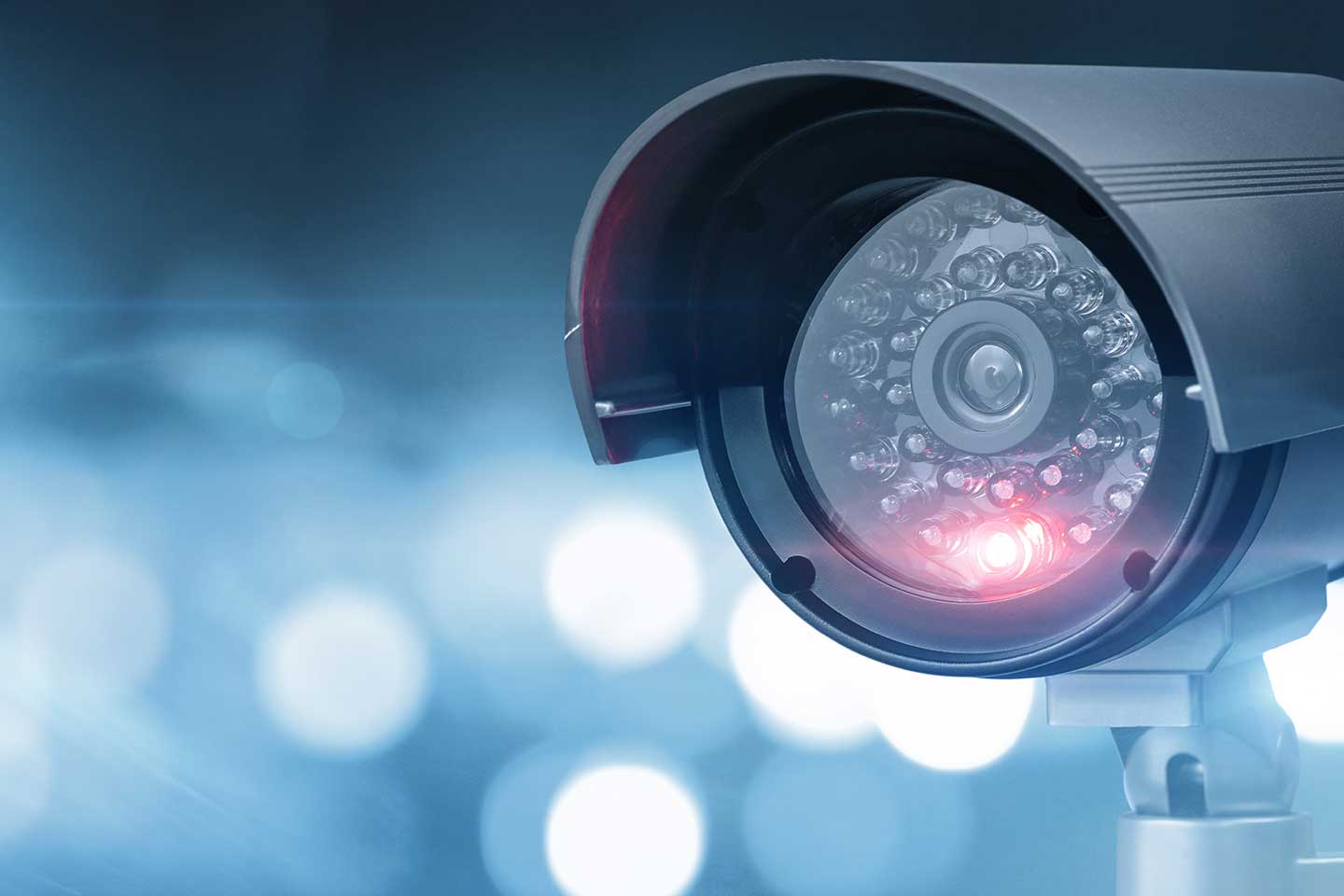 Kamera rechts im Bild, zur Videoüberwachung von Arbeitnehmern, natürlich mit Einhaltung der Datenschutz Richtlinien. Der Hintergrund ist blau weiß gepixelt.