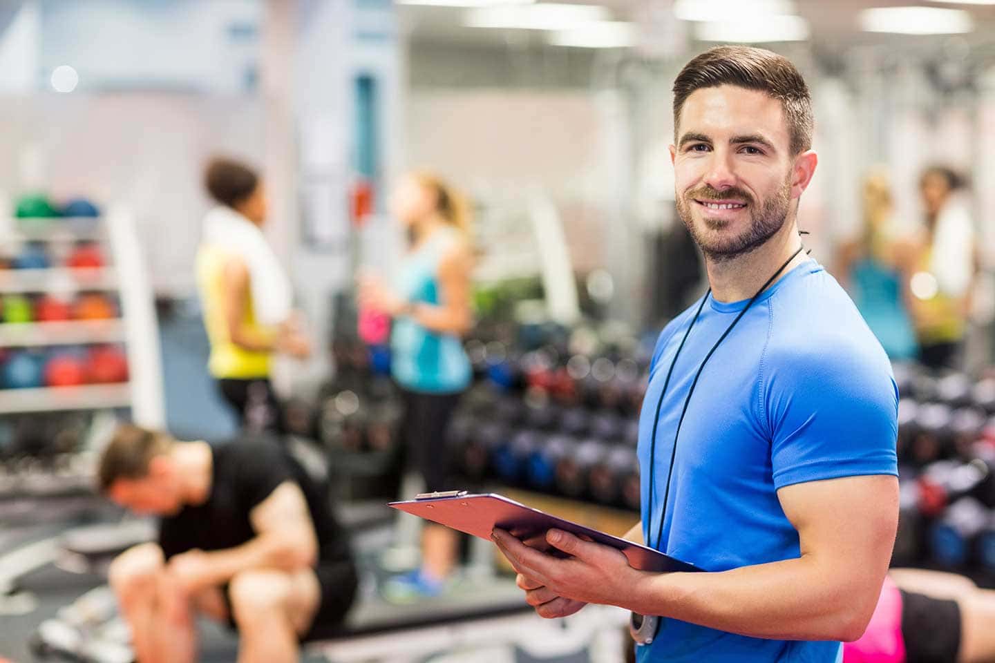 Smarter Fitnesstrainer erstellt eine Checkliste zum Thema Datenschutz im Fitnesstudio, hinter ihm sind schemenhaft trainierende Personen zu sehen.